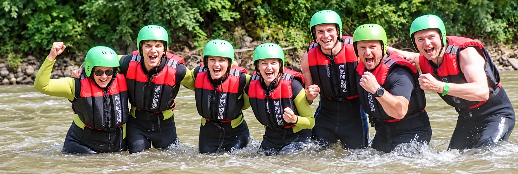Sieben Teammitglieder beim gemeinsamen Rafting im Fluss